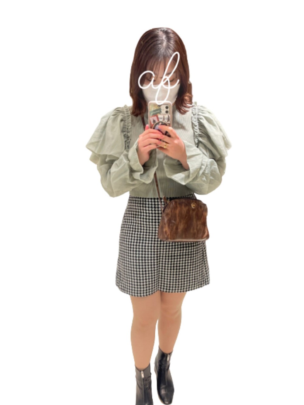 ブラック系のスカート、ブラウン系のショルダーバッグ、グリーン系のトップスを着用したレディースの冬コーディネートの1枚目の写真