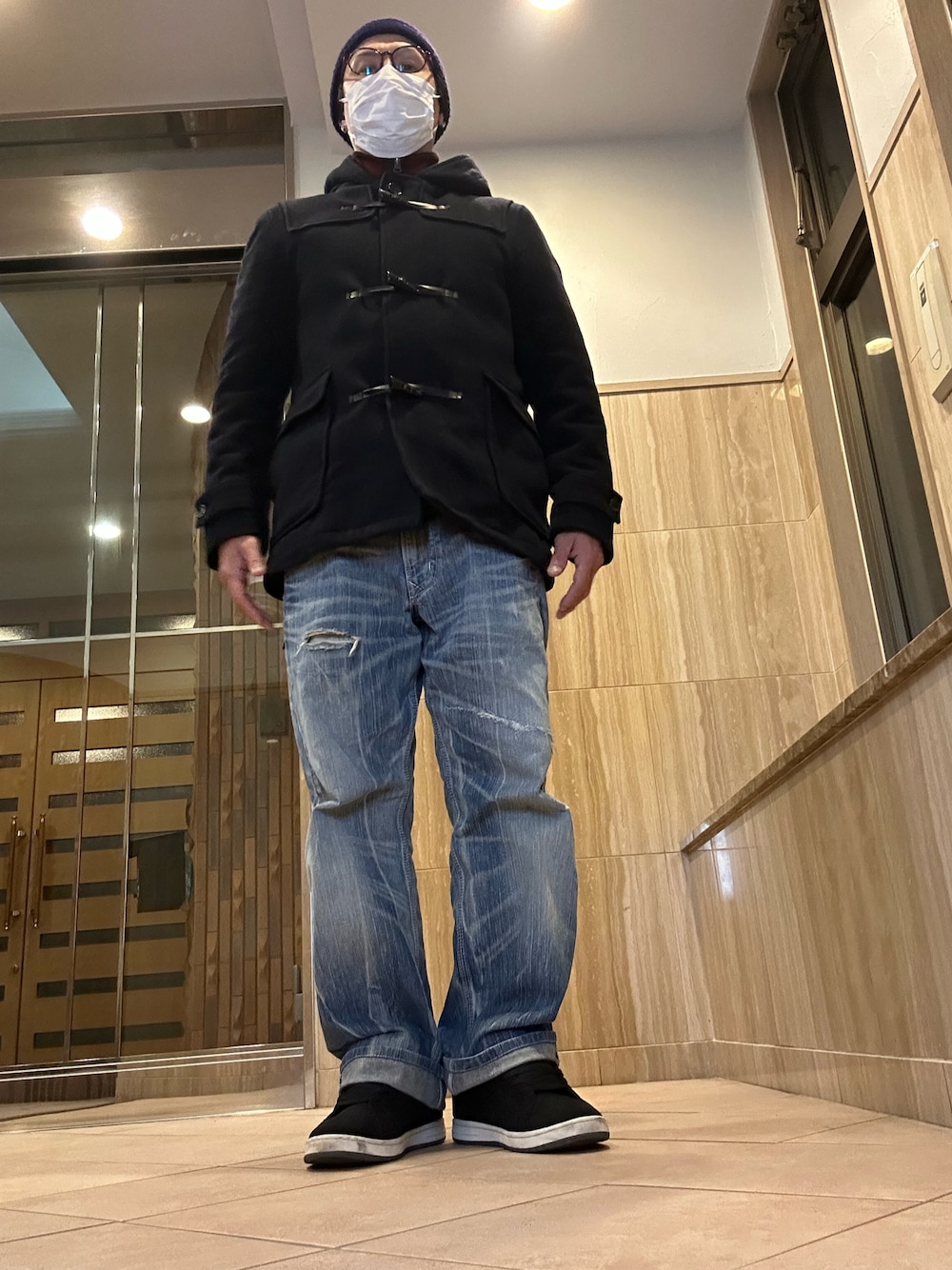 ブラック系のダッフルコート、ブルー系のデニムパンツ、ブラック系のスニーカーを着用したメンズの冬コーディネートの1枚目の写真