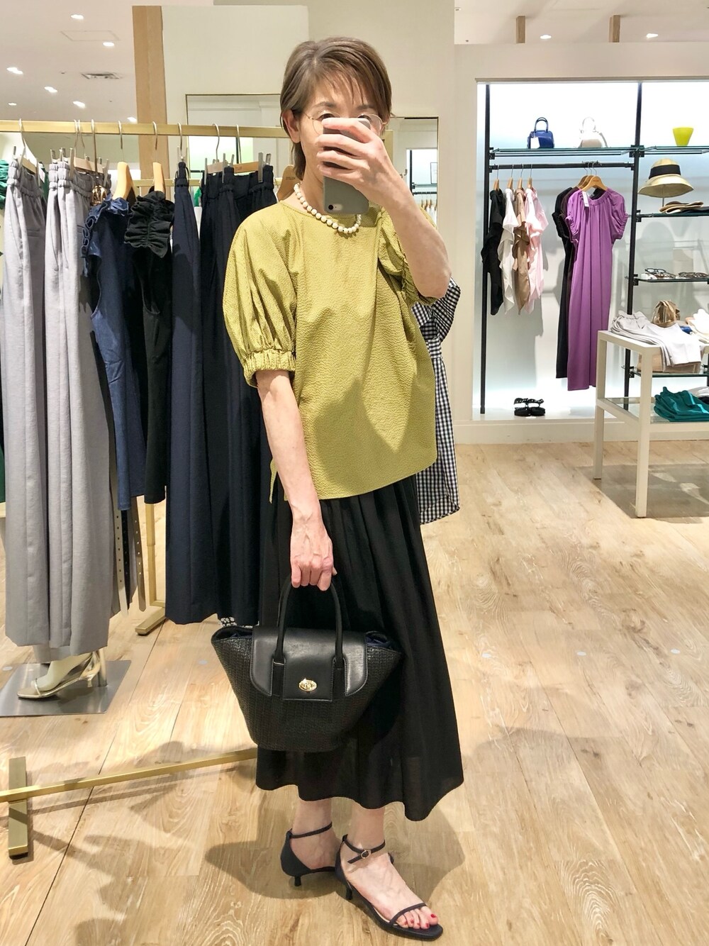 イエロー系のシャツ/ブラウス、ブラック系のスカート、ブラック系のかごバッグを着用したレディースの夏コーディネートの1枚目の写真