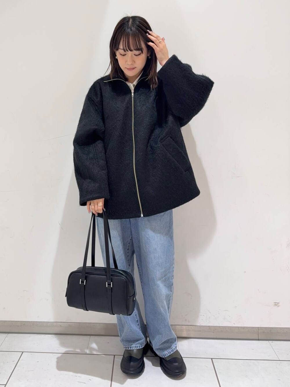 ブルー系のデニムパンツ、ブラック系のボストンバッグ、グリーン系のブーツを着用したレディースの冬コーディネートの1枚目の写真