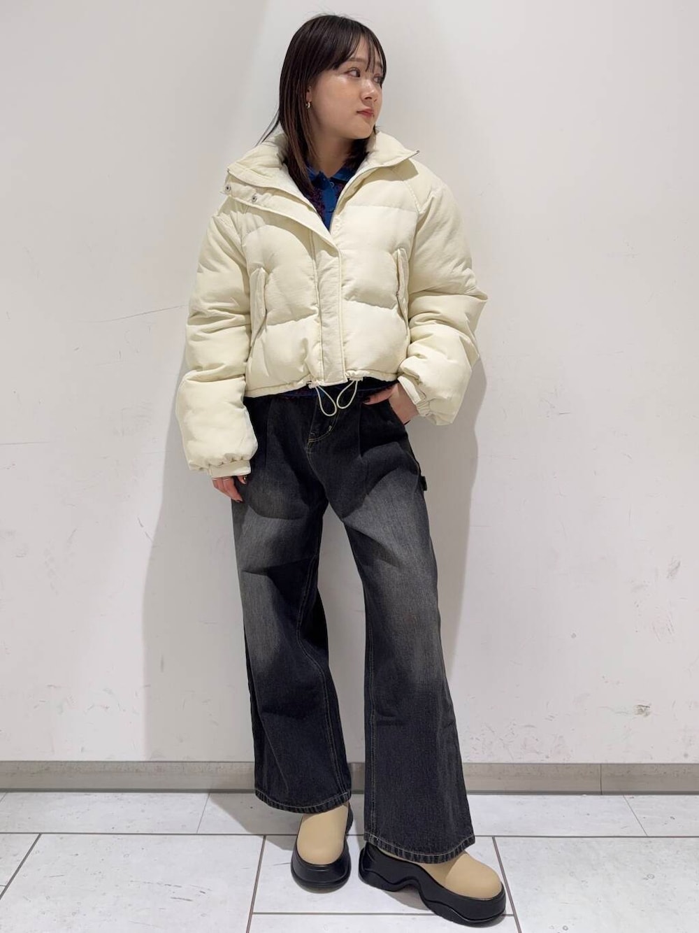 ブルー系のニット/セーター、ホワイト系のダウンジャケット/コート、ブラック系のデニムパンツを着用したレディースの冬コーディネートの1枚目の写真