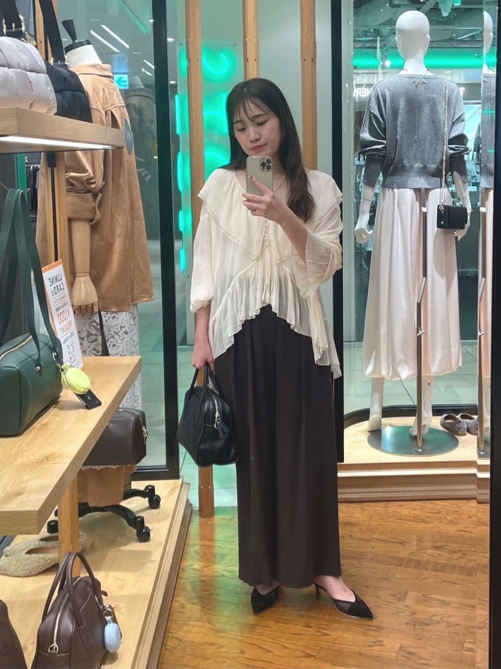 ブラウン系のスラックス、ブラック系のボストンバッグ、ブラック系のパンプスを着用したレディースの秋コーディネートの1枚目の写真