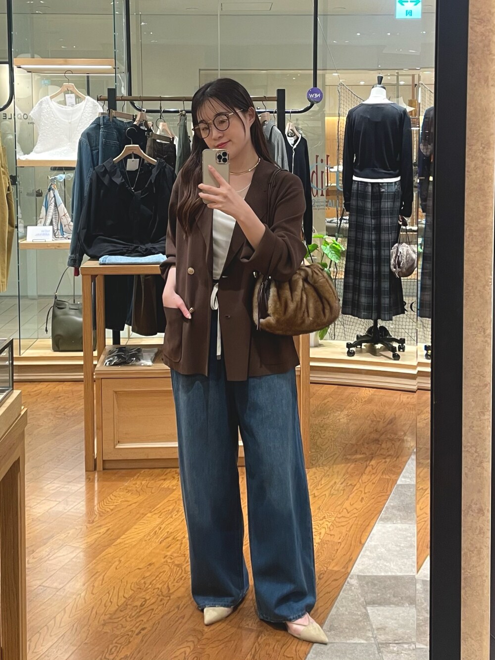 イエロー系のハンドバッグ、ブルー系のデニムパンツ、ベージュ系のパンプスを着用したレディースの夏コーディネートの1枚目の写真