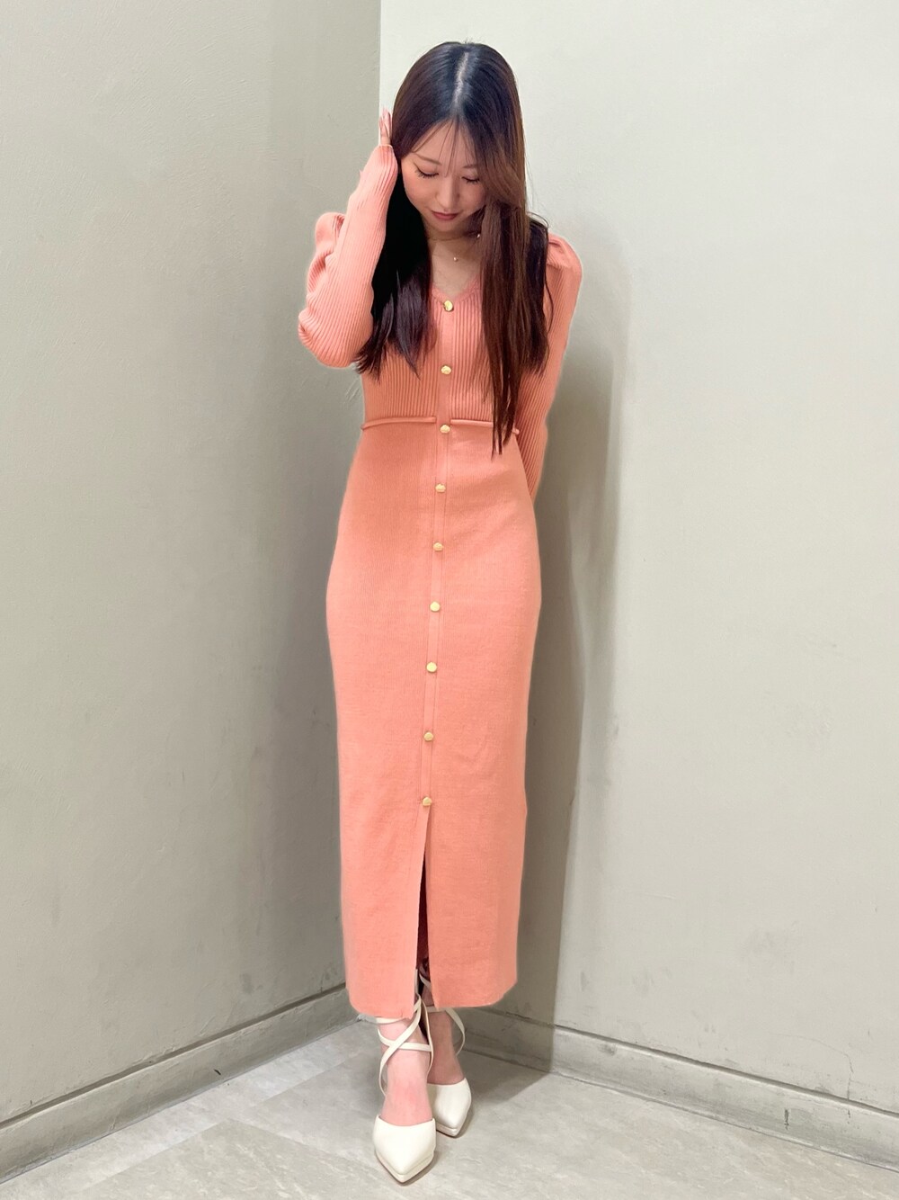 ホワイト系のパンプス、オレンジ系のワンピース、ゴールド系のネックレスを着用したレディースの冬コーディネートの1枚目の写真
