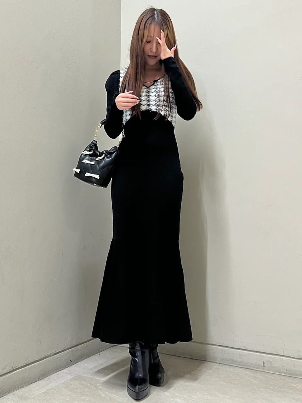 ブラック系のワンピース、ブラック系のブーツ、その他のハンドバッグを着用したレディースの秋コーディネートの1枚目の写真