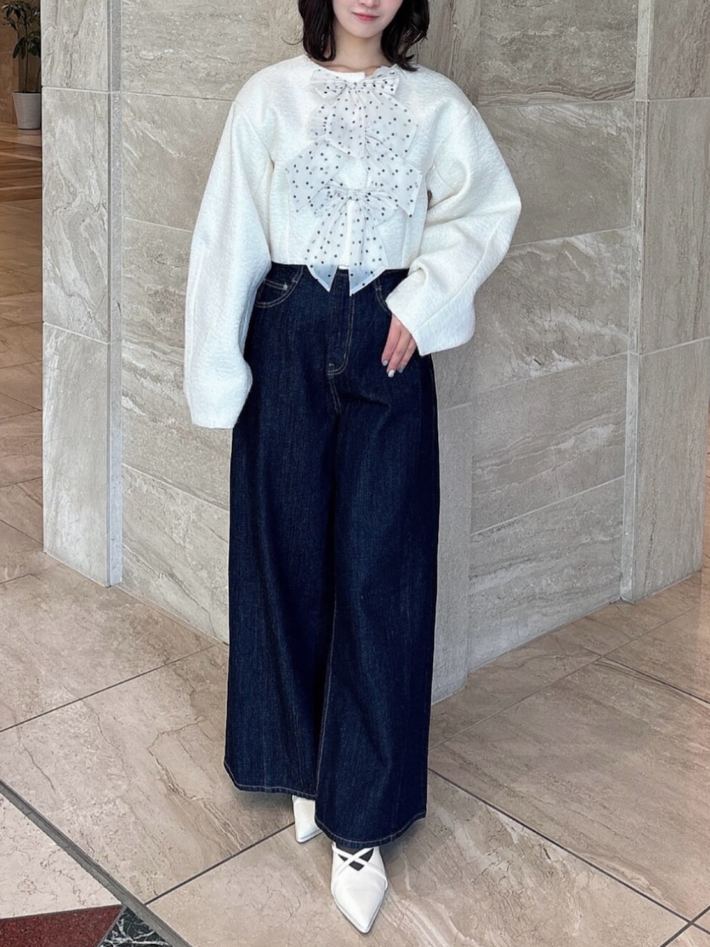 ホワイト系のパンプス、ブルー系のデニムパンツ、ホワイト系のブルゾンを着用したレディースの冬コーディネートの1枚目の写真