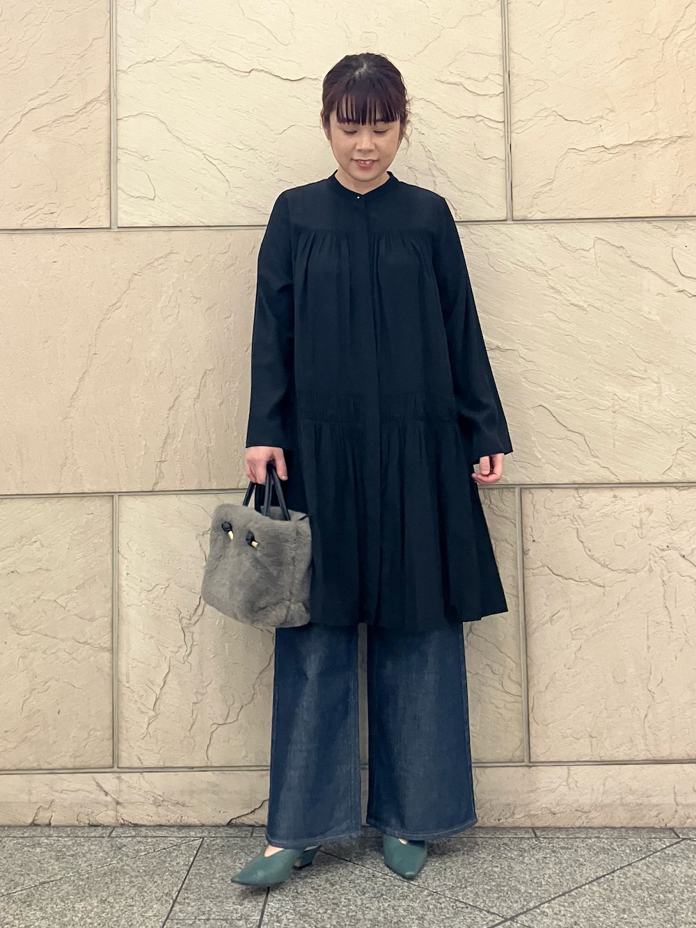 ブラック系のワンピース、ブラウン系のハンドバッグ、ブルー系のデニムパンツを着用したレディースの秋コーディネートの1枚目の写真