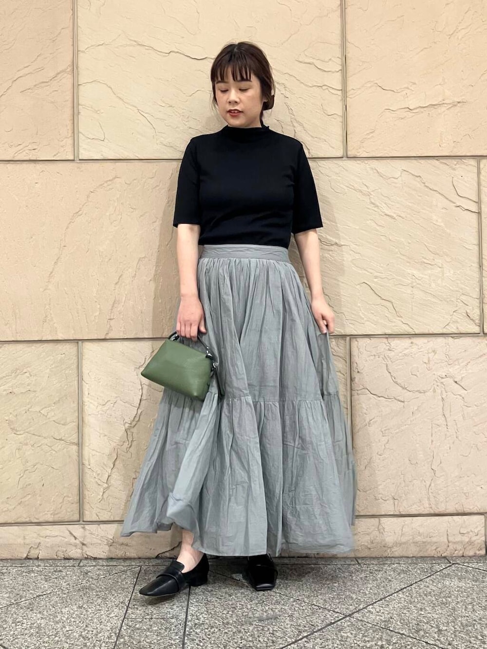 ブラック系のTシャツ/カットソー、グレー系のスカート、グリーン系のショルダーバッグを着用したレディースの夏コーディネートの1枚目の写真
