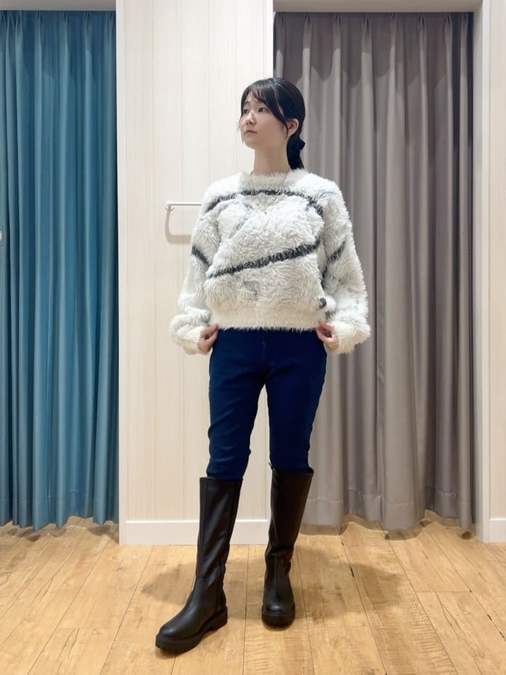 ホワイト系のニット/セーター、ブルー系のその他パンツ、ブラック系のブーツを着用したレディースの冬コーディネートの1枚目の写真