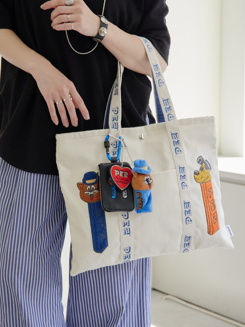 ホワイト系のトートバッグ、ブラック系のTシャツ/カットソー、ブラック系のキーケース/キーアクセサリーを着用したレディースの春コーディネートの1枚目の写真