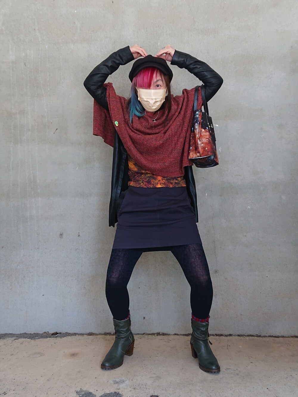 ブラック系のトートバッグ、ブラック系のスカート、レッド系のポンチョを着用したレディースの春コーディネートの2枚目の写真