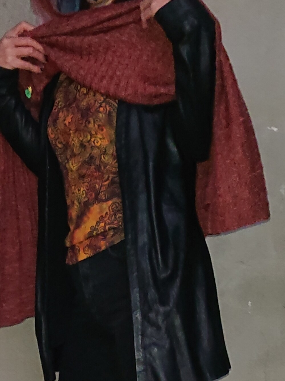 レッド系のポンチョ、ブラック系のジャケット/アウター、ブラック系のデニムパンツを着用したレディースの春コーディネートの2枚目の写真