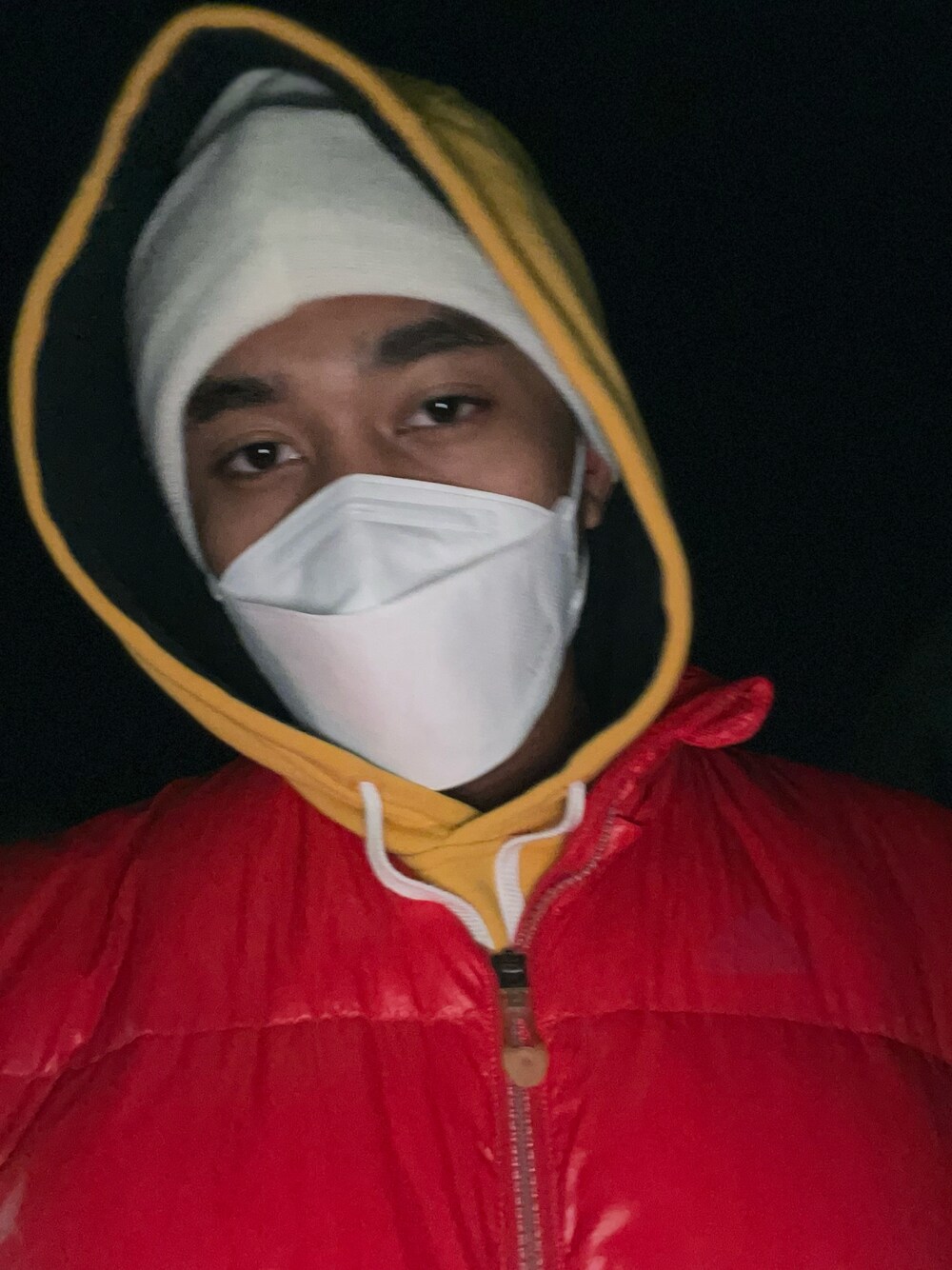 レッド系のダウンジャケット/コート、イエロー系のパーカー、ホワイト系のハットを着用したメンズの冬コーディネートの1枚目の写真