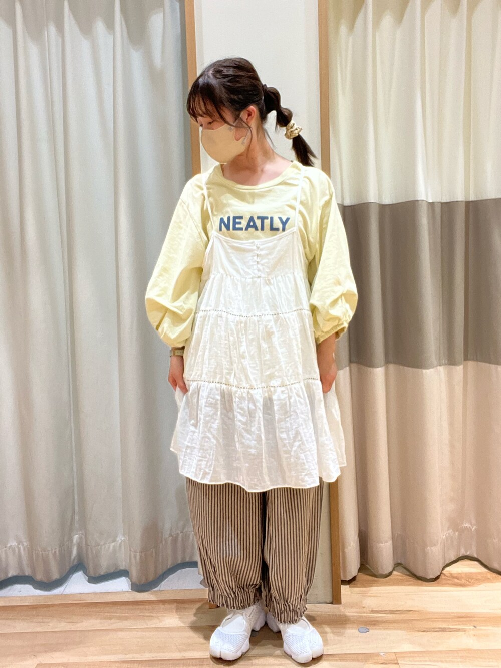イエロー系のTシャツ/カットソー、ホワイト系のチュニック、グレー系のパンツを着用したレディースの春コーディネートの1枚目の写真