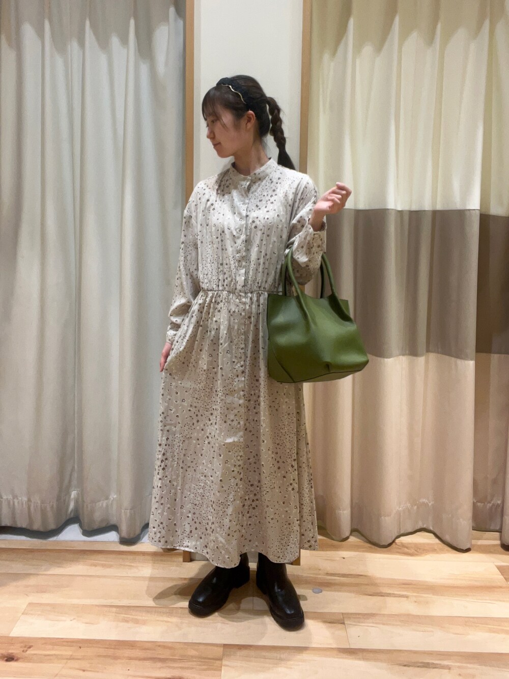 グリーン系のハンドバッグ、ベージュ系のワンピース、ブラック系のドレスシューズを着用したレディースの秋コーディネートの1枚目の写真