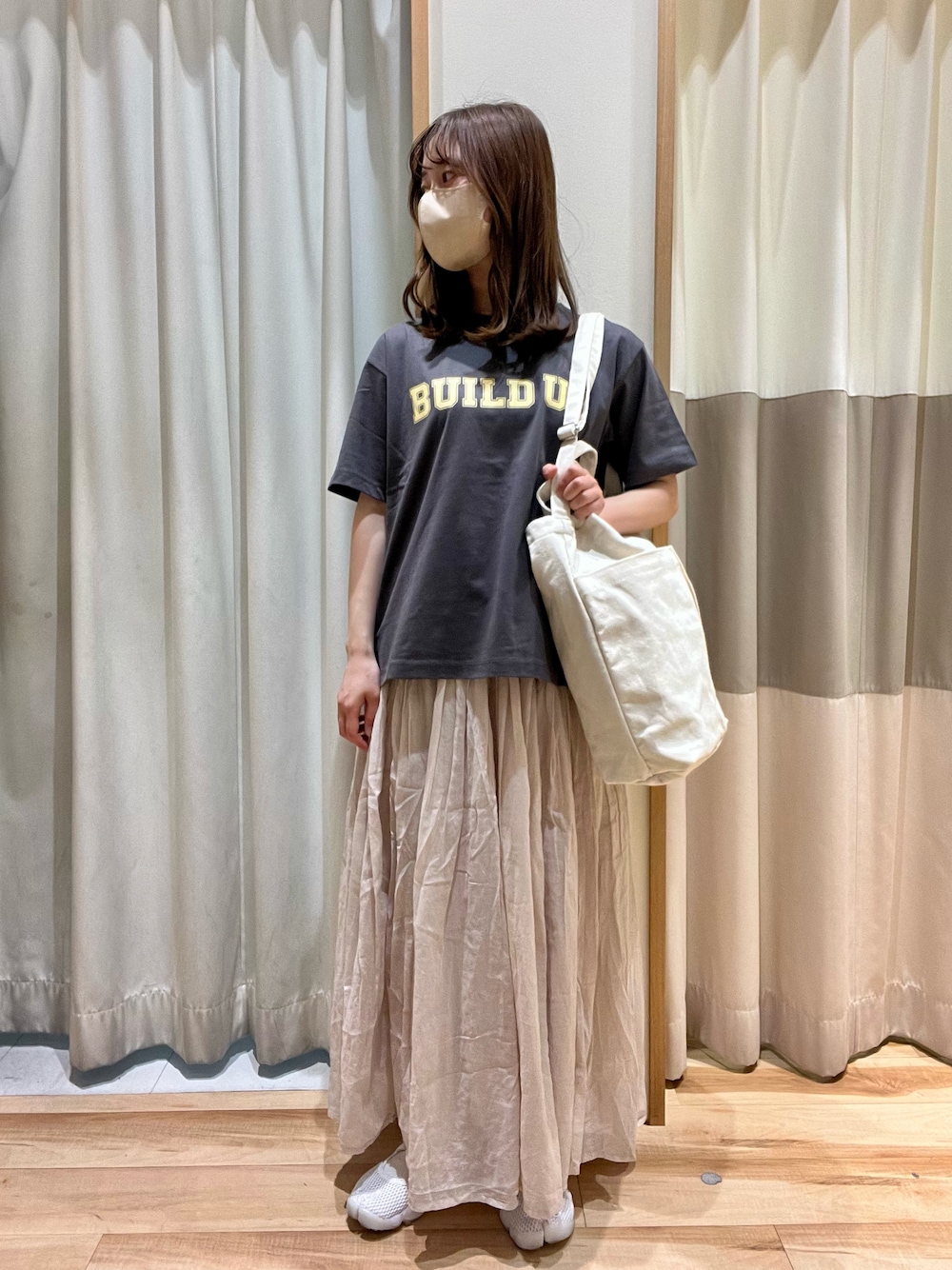 グレー系のTシャツ/カットソー、ホワイト系のハンドバッグ、グレー系のスカートを着用したレディースの春コーディネートの1枚目の写真