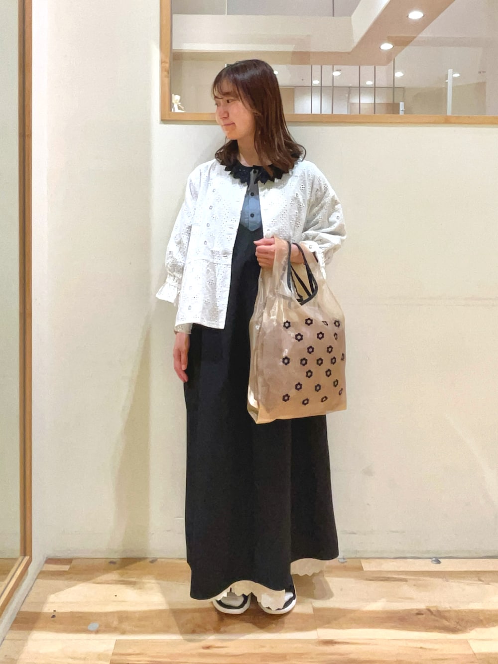 ベージュ系のハンドバッグ、ブラック系のサンダル、ブラック系のワンピースを着用したレディースの春コーディネートの1枚目の写真