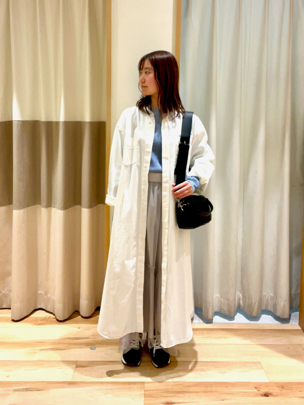 ブルー系のニット/セーター、グレー系のスカート、ホワイト系のワンピースを着用したレディースの春コーディネートの1枚目の写真