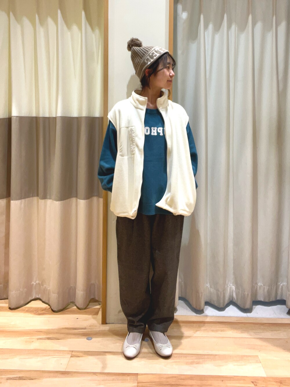グレー系のその他パンツ、グリーン系のニット/セーター、ホワイト系のベストを着用したレディースの秋コーディネートの1枚目の写真