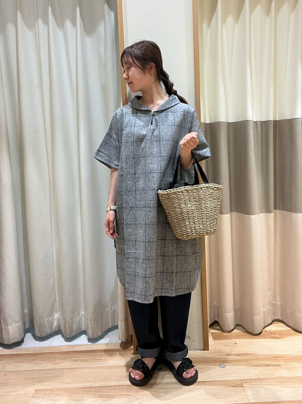 ブラック系のハンドバッグ、ブルー系のデニムパンツ、ブラック系のチュニックを着用したレディースの夏コーディネートの1枚目の写真