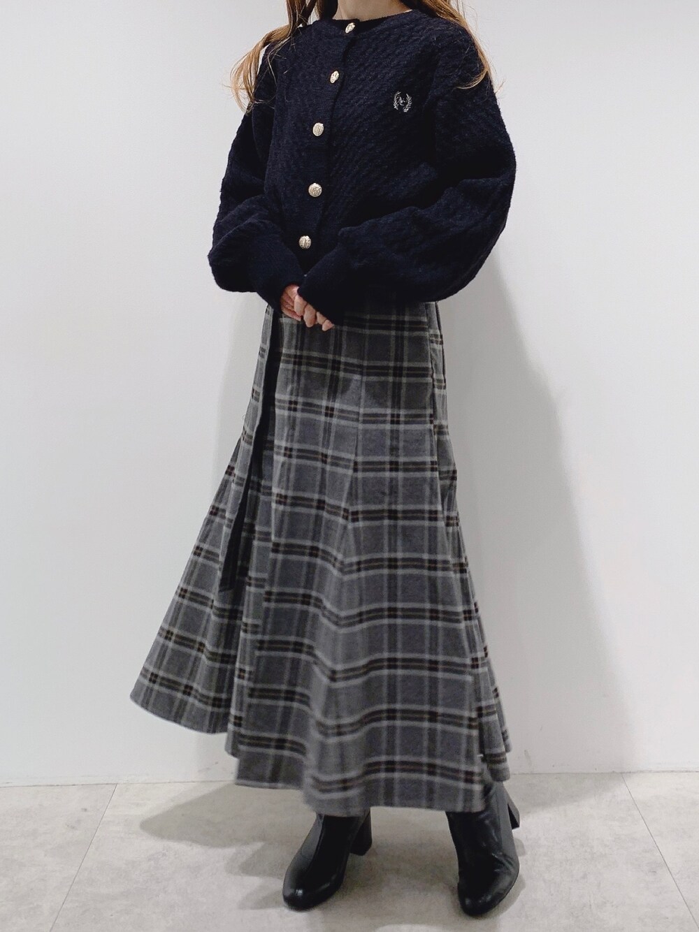 ブラック系のカーディガン/ボレロ、グレー系のスカート、ブラック系のブーツを着用したレディースの冬コーディネートの1枚目の写真