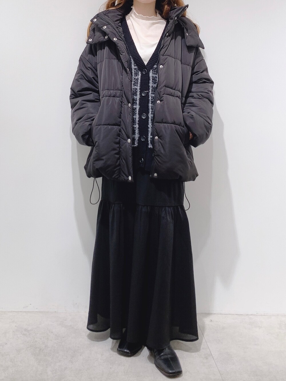 ブラック系のダウンジャケット/コート、ホワイト系のTシャツ/カットソー、ブラック系のカーディガン/ボレロを着用したレディースの冬コーディネートの1枚目の写真