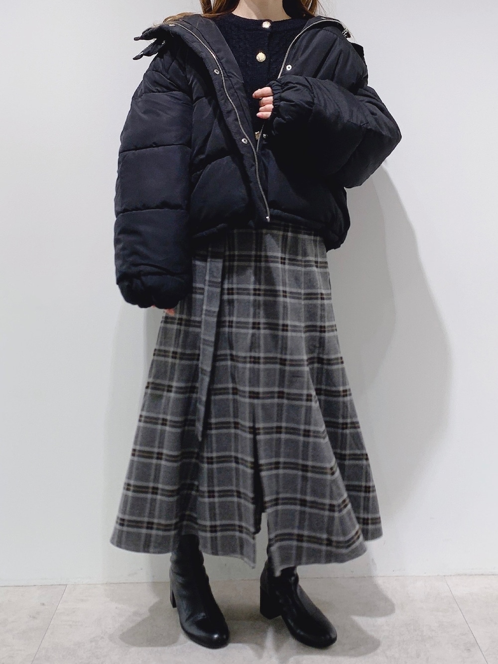 ブラック系のダウンジャケット/コート、グレー系のスカート、ブラック系のブーツを着用したレディースの冬コーディネートの1枚目の写真