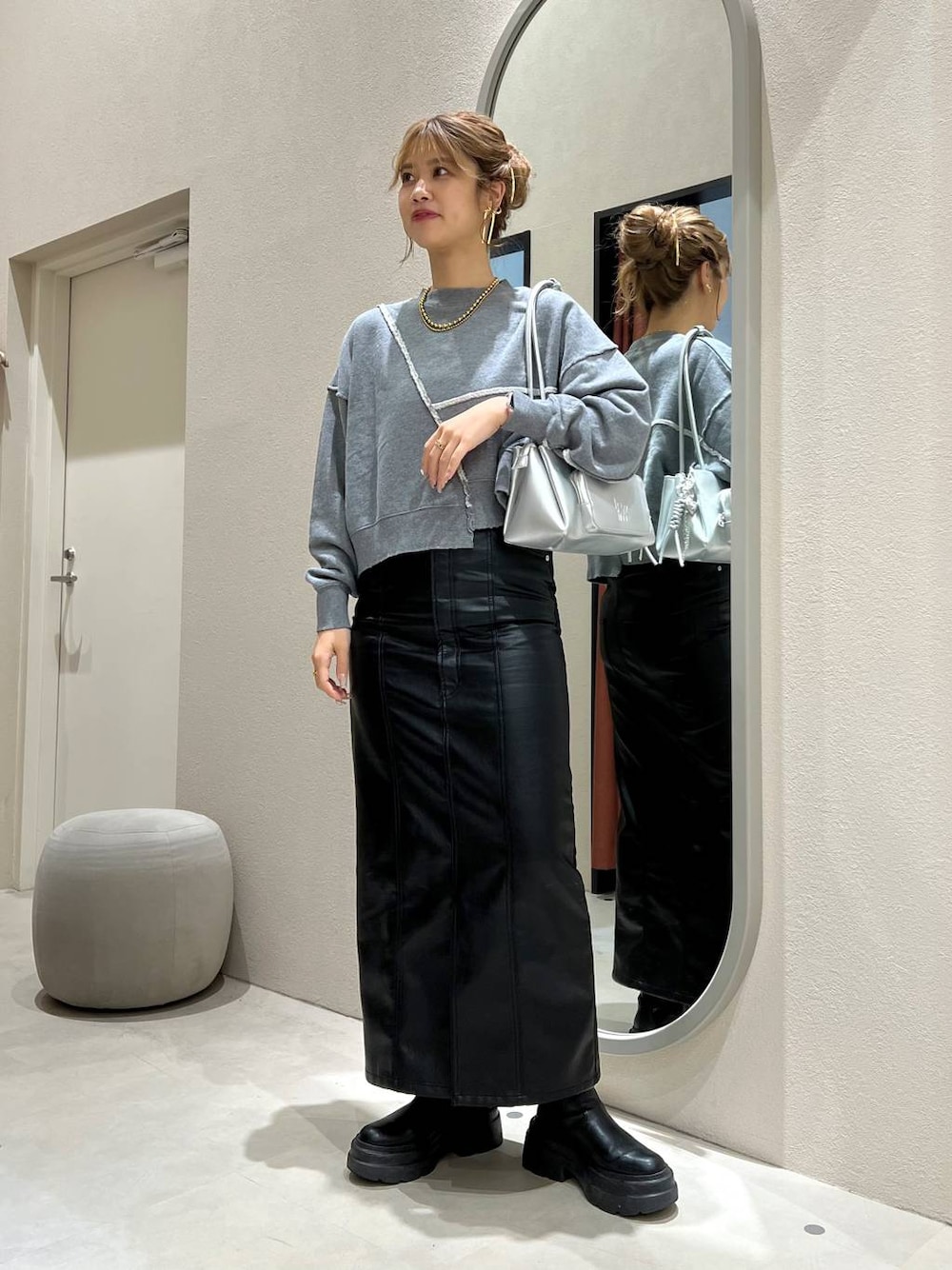 グレー系のスウェット、シルバー系のショルダーバッグ、ブラック系のジャンパースカートを着用したレディースの秋コーディネートの1枚目の写真