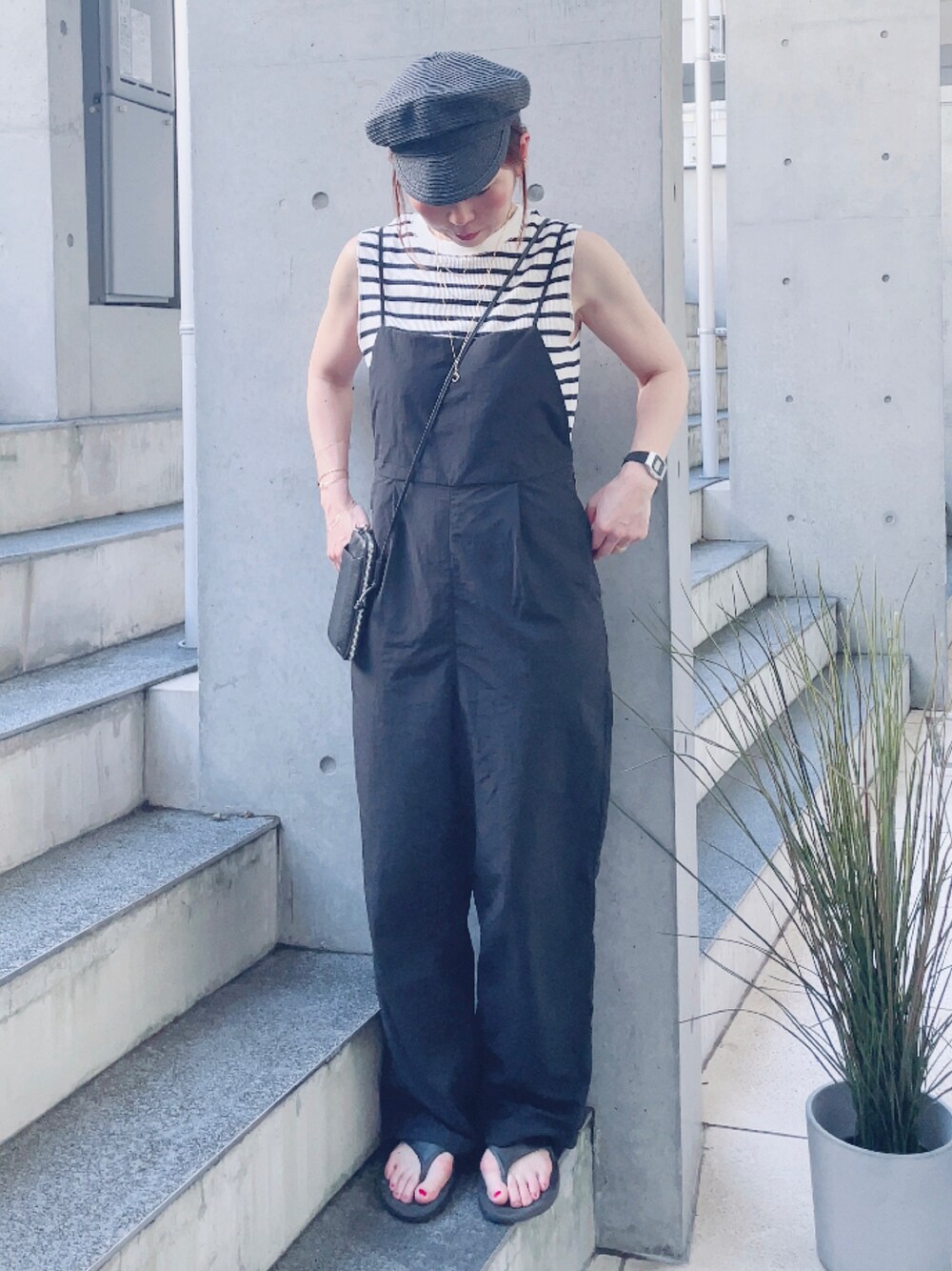 ブラック系のサロペット/オーバーオール、ホワイト系のTシャツ/カットソー、ブラック系のサンダルを着用したレディースの夏コーディネートの1枚目の写真