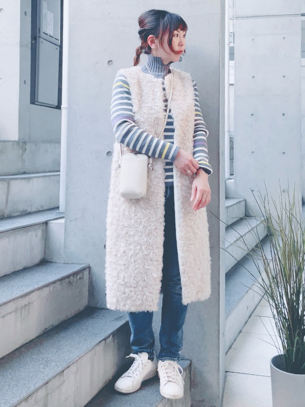 グレー系のニット/セーター、ブルー系のデニムパンツ、ホワイト系のショルダーバッグを着用したレディースの秋コーディネートの1枚目の写真