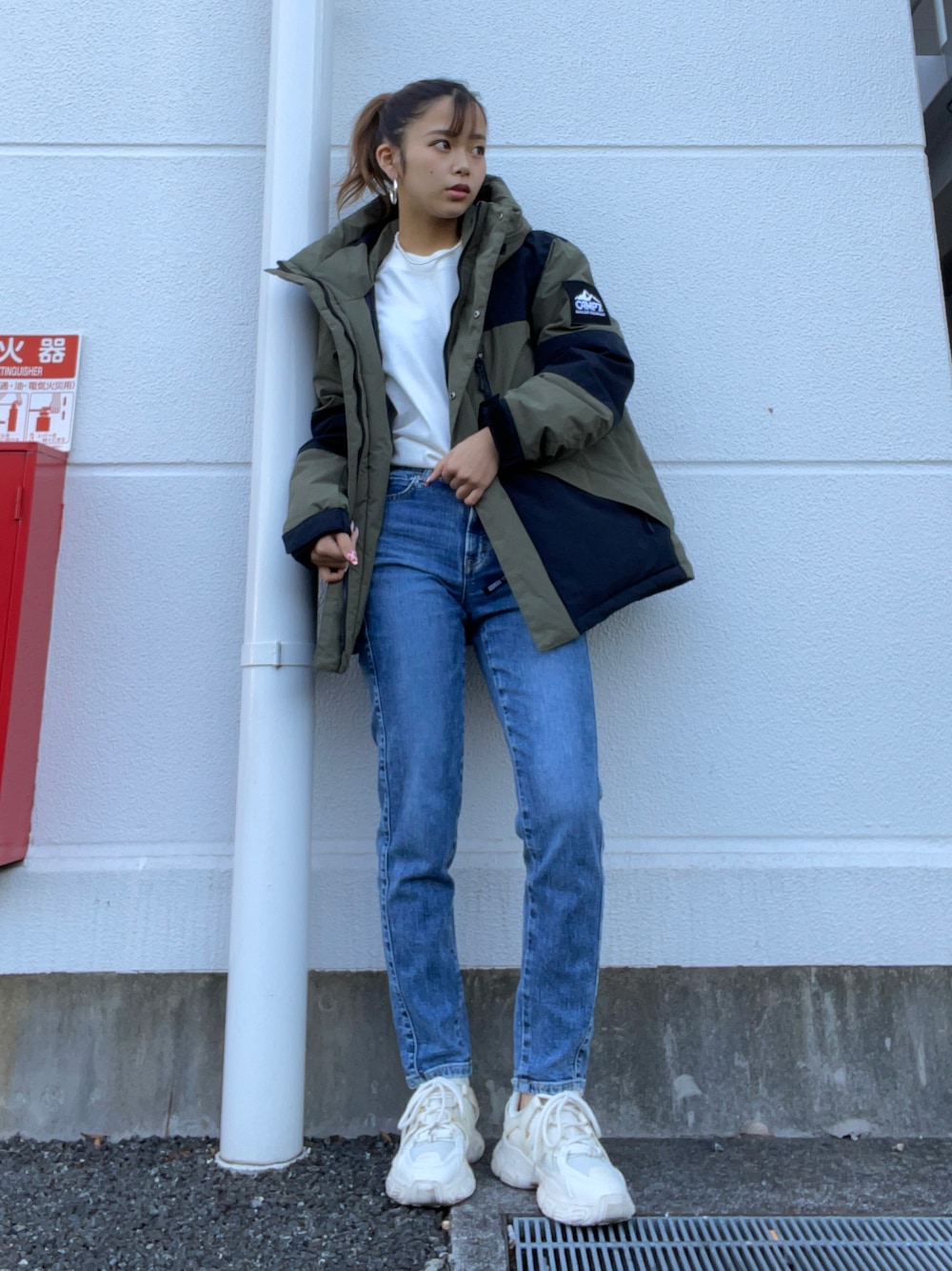 ホワイト系のTシャツ/カットソー、グリーン系のダウンジャケット/コート、ブルー系のデニムパンツを着用したレディースの秋コーディネートの1枚目の写真