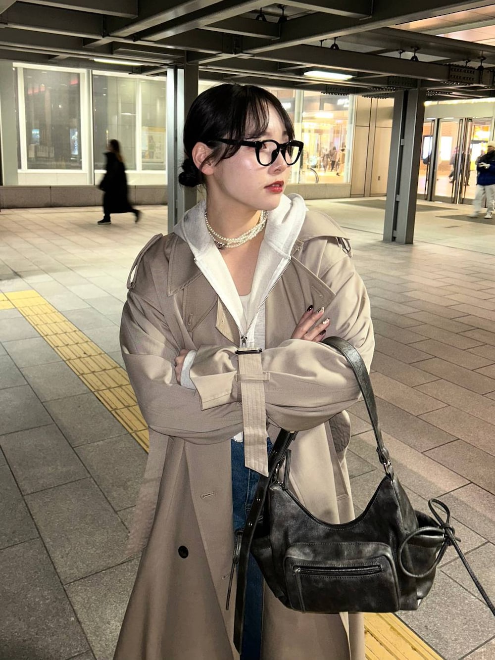 ブラック系のスニーカー、ブルー系のデニムパンツ、ブラック系のショルダーバッグを着用したレディースの春コーディネートの1枚目の写真