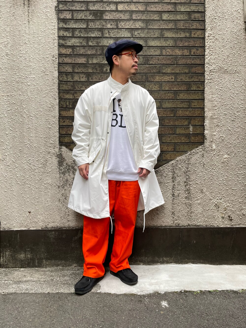 ホワイト系のモッズコート、オレンジ系のチノパンツを着用したメンズの春コーディネートの1枚目の写真