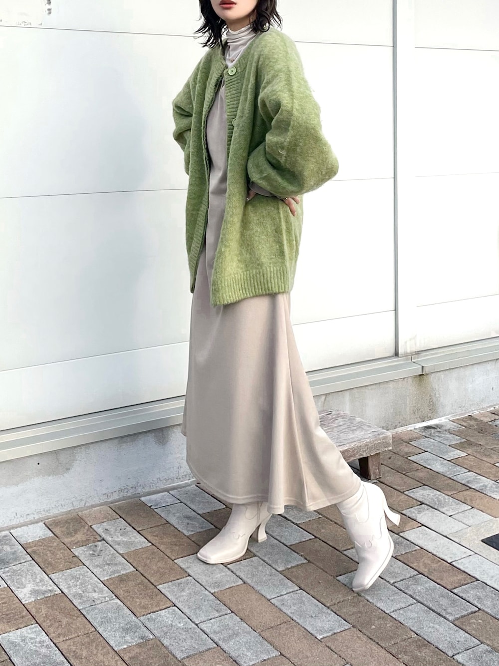 グリーン系のカーディガン/ボレロ、ベージュ系のワンピース、ベージュ系のTシャツ/カットソーを着用したレディースの冬コーディネートの1枚目の写真