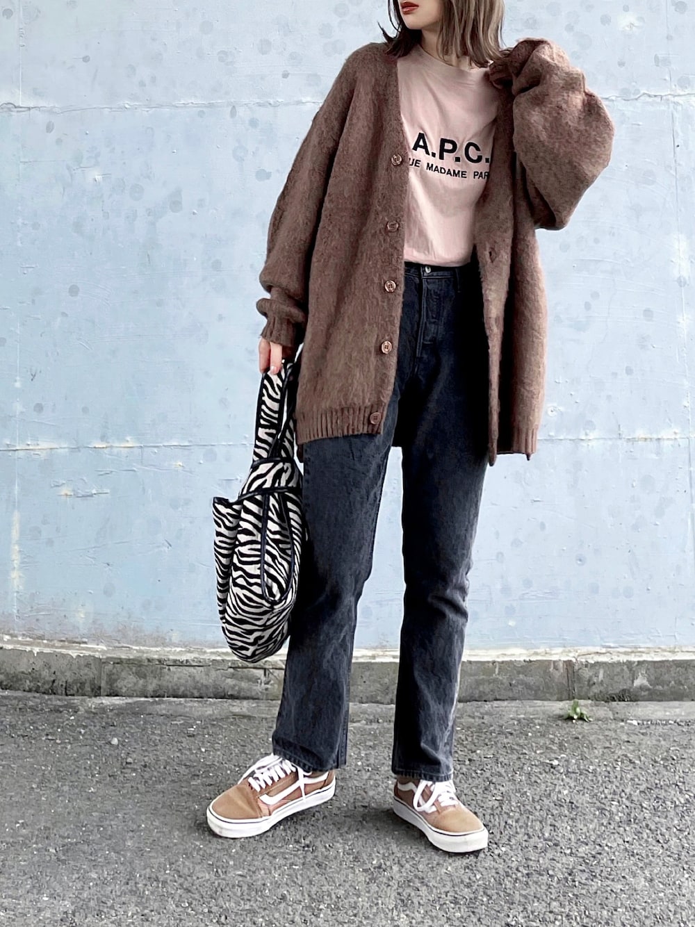 ブラウン系のカーディガン/ボレロ、ベージュ系のTシャツ/カットソー、グレー系のデニムパンツを着用したレディースの秋コーディネートの1枚目の写真