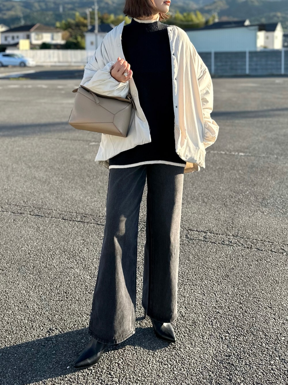 ホワイト系のダウンジャケット/コート、ブラック系のニット/セーター、ブラック系のデニムパンツを着用したレディースの秋コーディネートの1枚目の写真