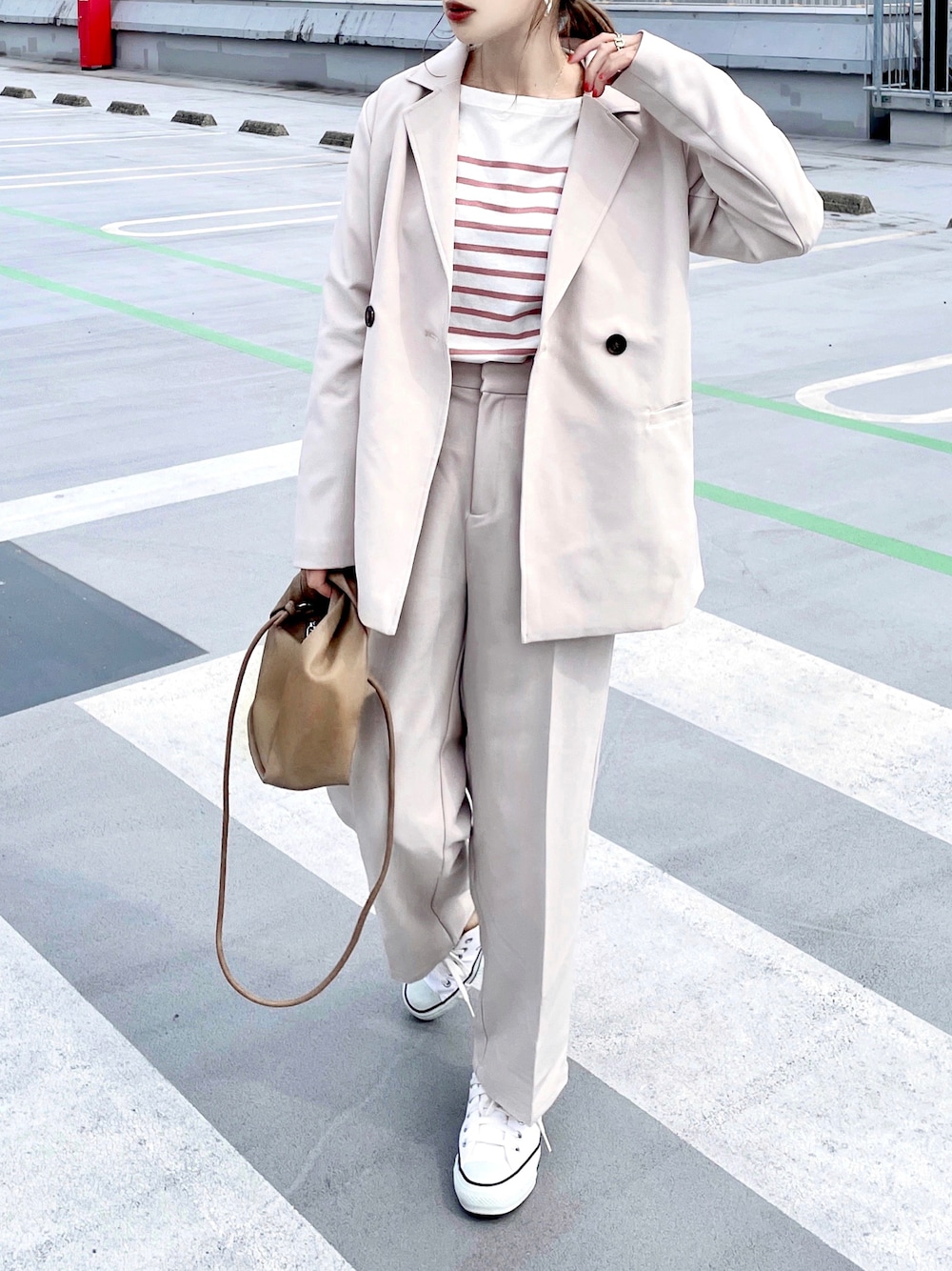 ホワイト系のセットアップ、ピンク系のTシャツ/カットソー、ブラウン系のショルダーバッグを着用したレディースの春コーディネートの1枚目の写真