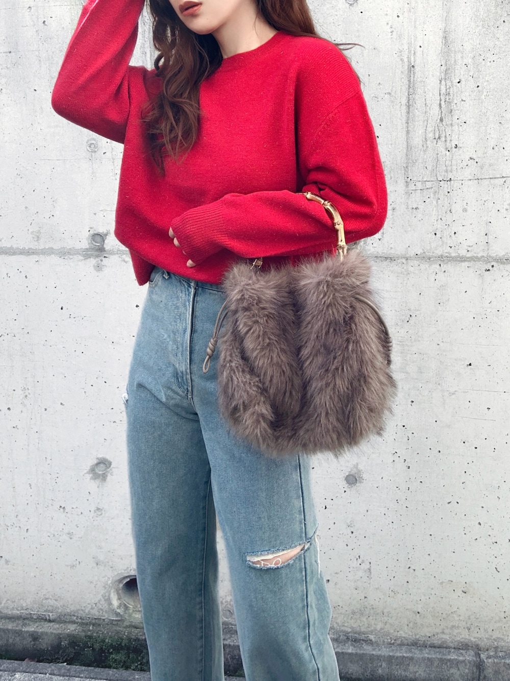 レッド系のニット/セーター、ブルー系のデニムパンツ、ブラウン系のハンドバッグを着用したレディースの冬コーディネートの1枚目の写真