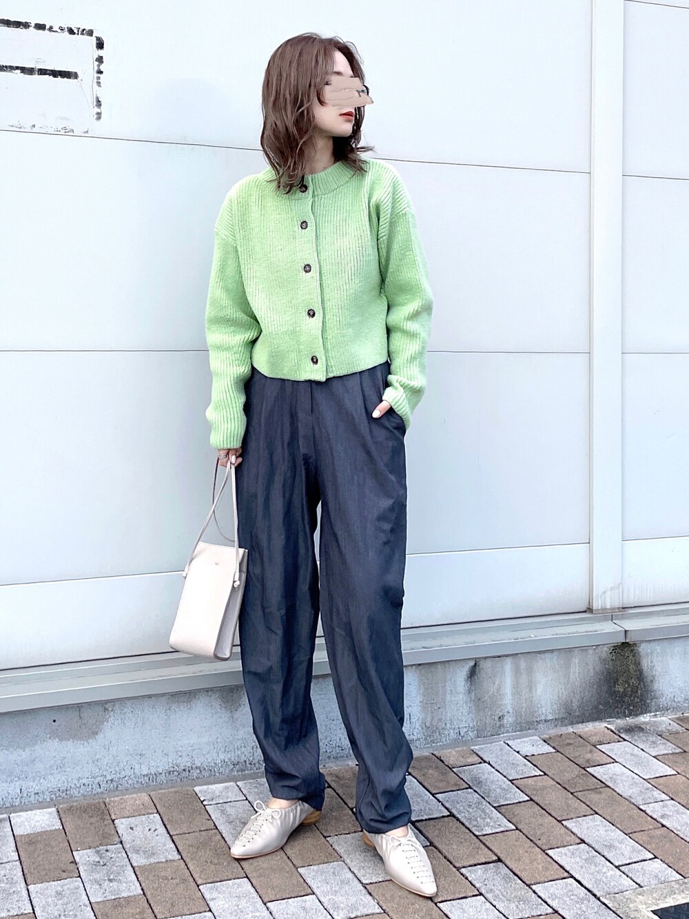 グリーン系のニット/セーター、グレー系のスラックス、グレー系のパンプスを着用したレディースの冬コーディネートの1枚目の写真