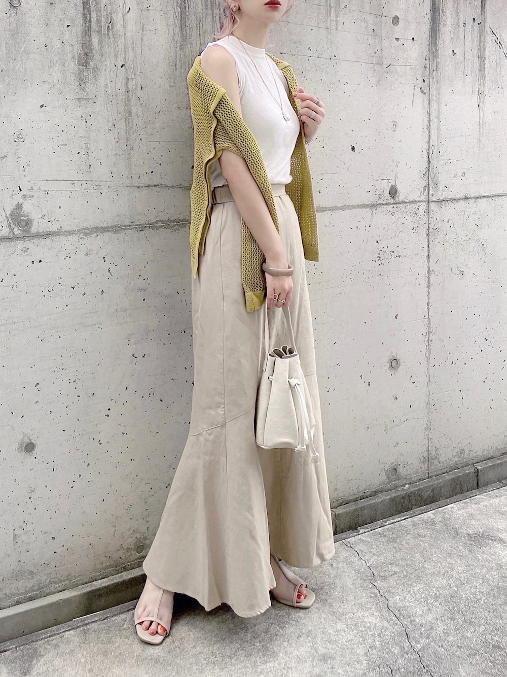 ベージュ系のスカート、グリーン系のニット/セーター、ホワイト系のハンドバッグを着用したレディースの夏コーディネートの1枚目の写真
