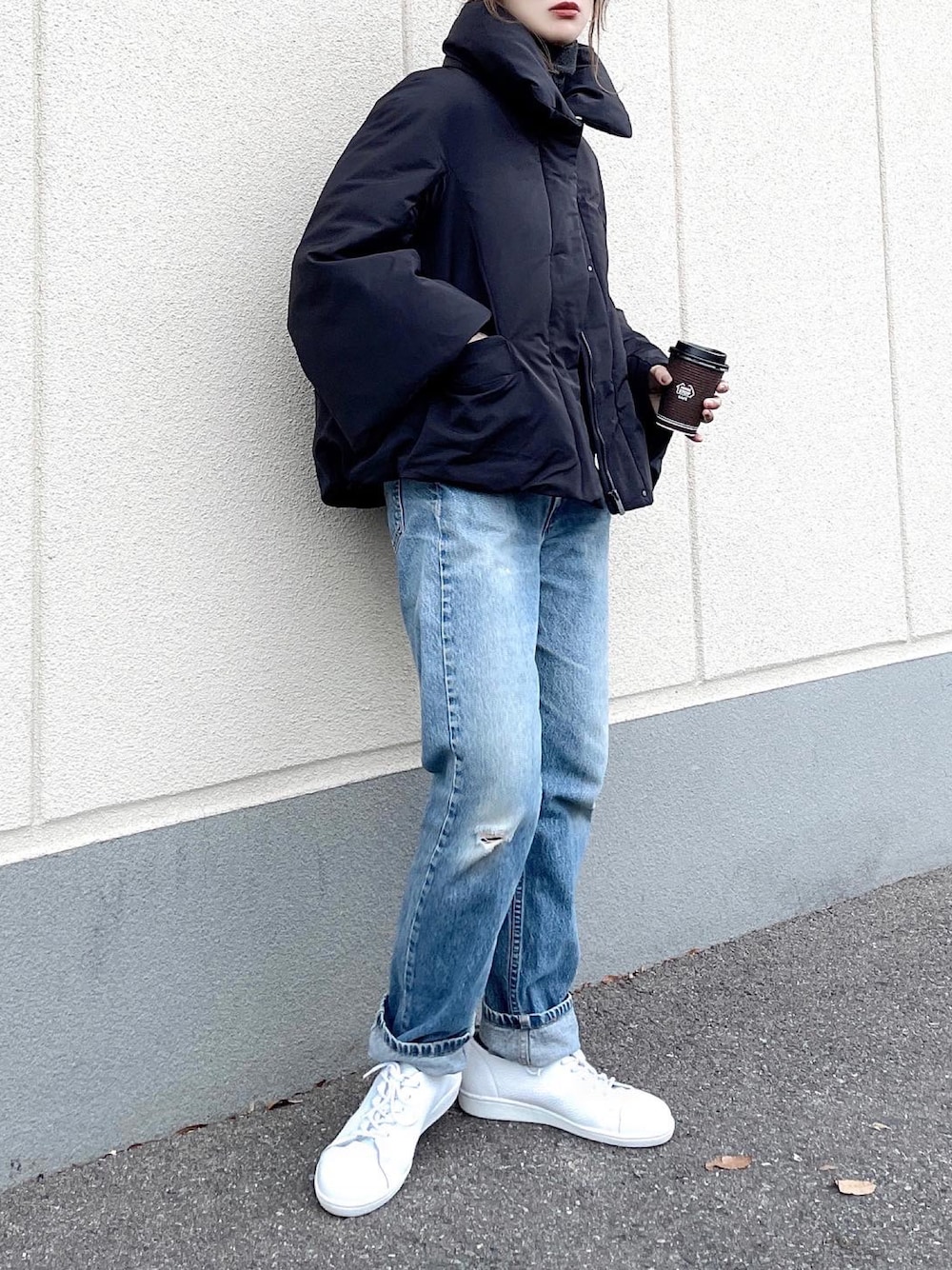 ホワイト系のスニーカー、ブラック系のジャケット/アウター、ブルー系のデニムパンツを着用したレディースの冬コーディネートの1枚目の写真