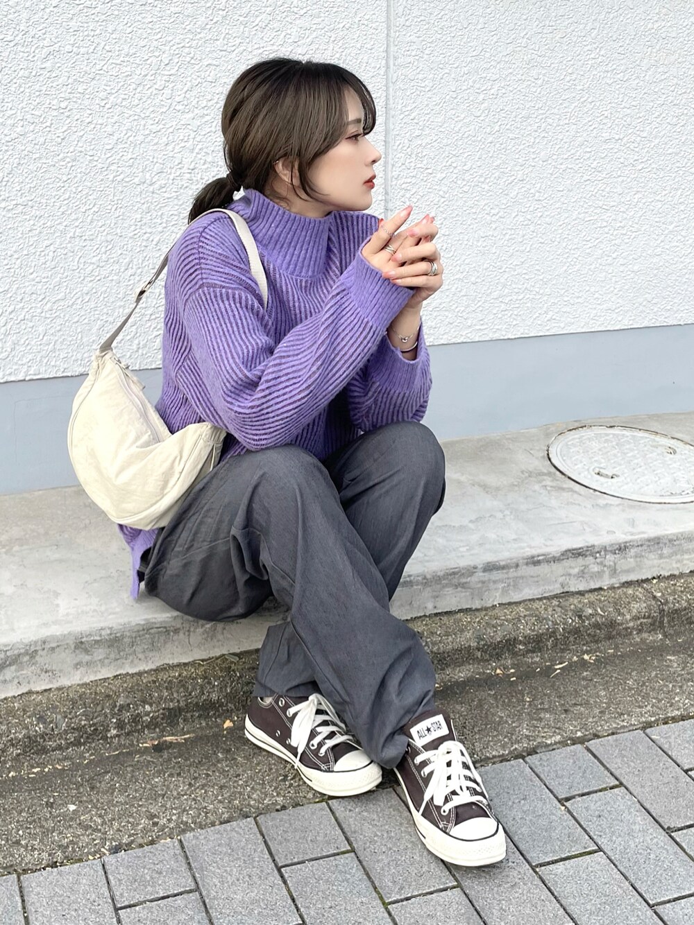 パープル系のニット/セーター、グレー系のスラックス、ブラック系のスニーカーを着用したレディースの冬コーディネートの1枚目の写真