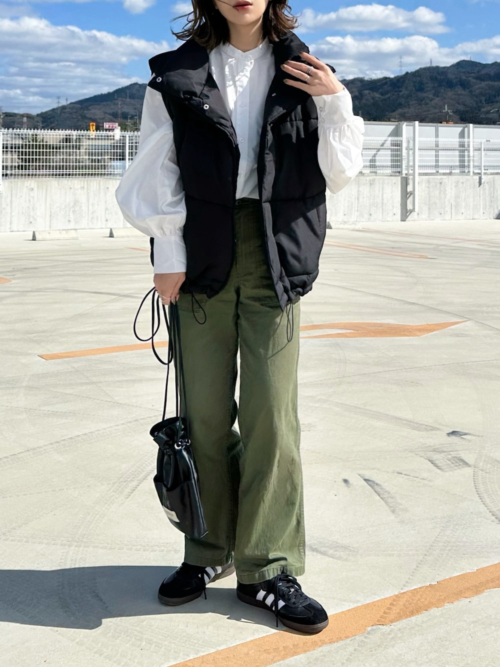 ホワイト系のシャツ/ブラウス、グリーン系のパンツ、ブラック系のショルダーバッグを着用したレディースの春コーディネートの1枚目の写真