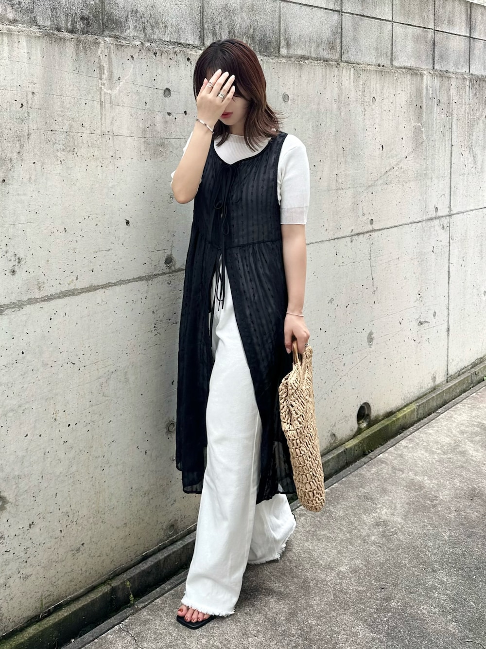 ホワイト系のニット/セーター、ホワイト系のデニムパンツ、ブラウン系のかごバッグを着用したレディースの夏コーディネートの1枚目の写真