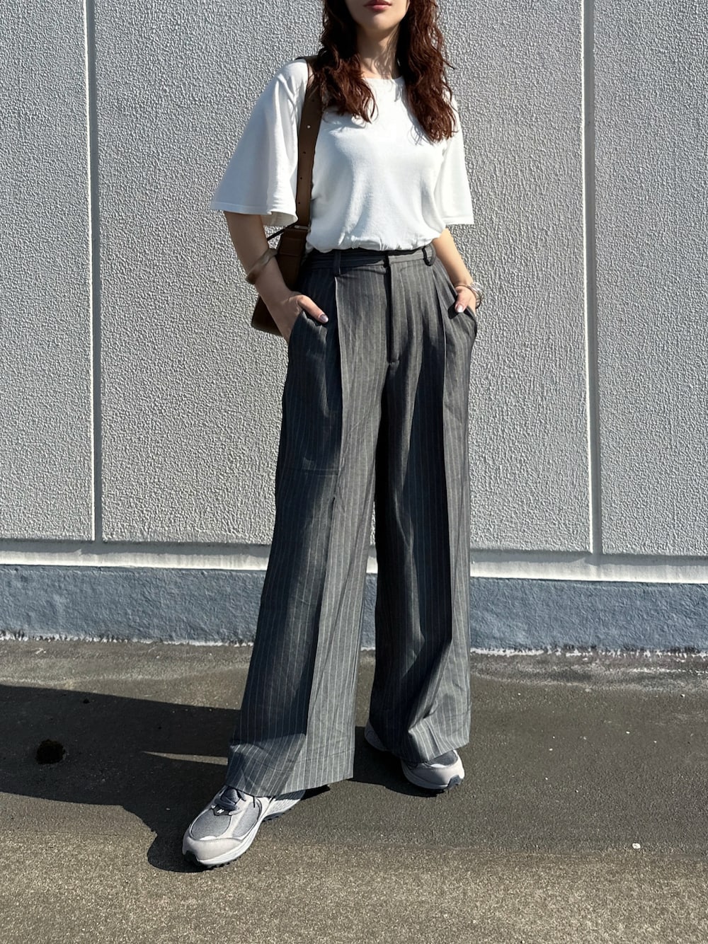 ホワイト系のニット/セーター、グレー系のその他パンツ、ブラウン系のバッグを着用したレディースの夏コーディネートの1枚目の写真