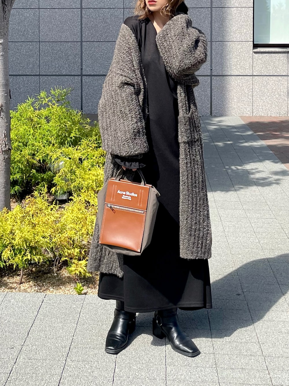 ブラック系のワンピース、ベージュ系のカーディガン/ボレロ、ブラウン系のバッグを着用したレディースの秋コーディネートの1枚目の写真