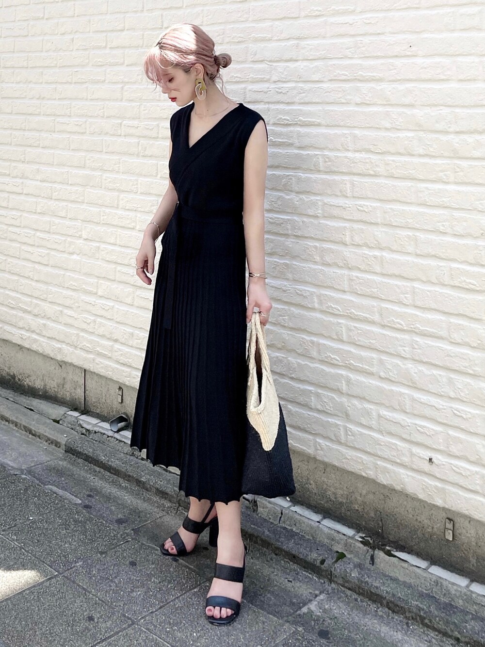 ブラック系のワンピース、ベージュ系のバッグ、ブラック系のサンダルを着用したレディースの夏コーディネートの1枚目の写真