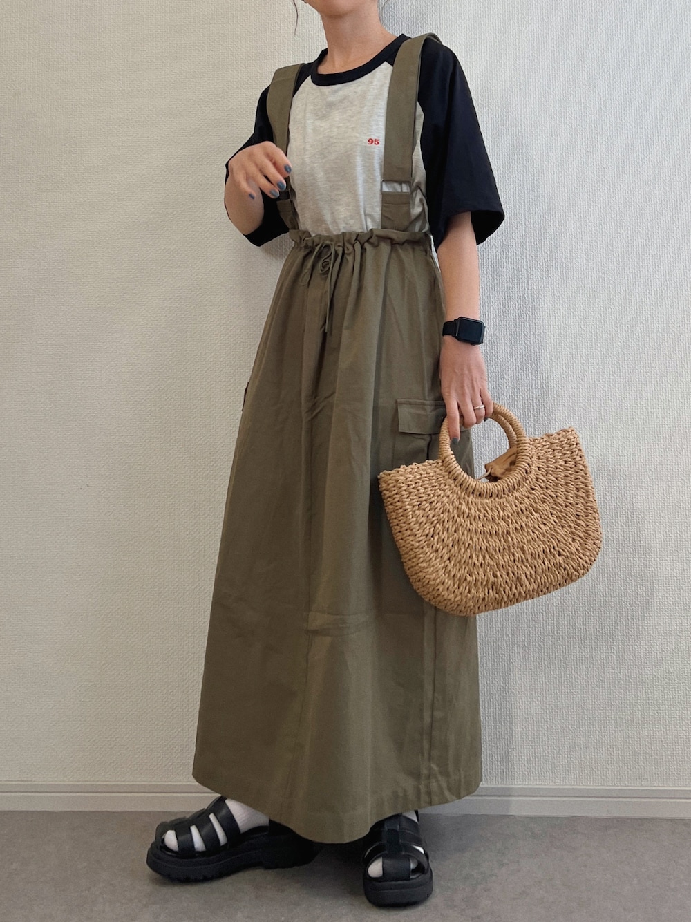 グリーン系のスカート、グレー系のTシャツ/カットソー、ベージュ系のかごバッグを着用したレディースの春コーディネートの1枚目の写真