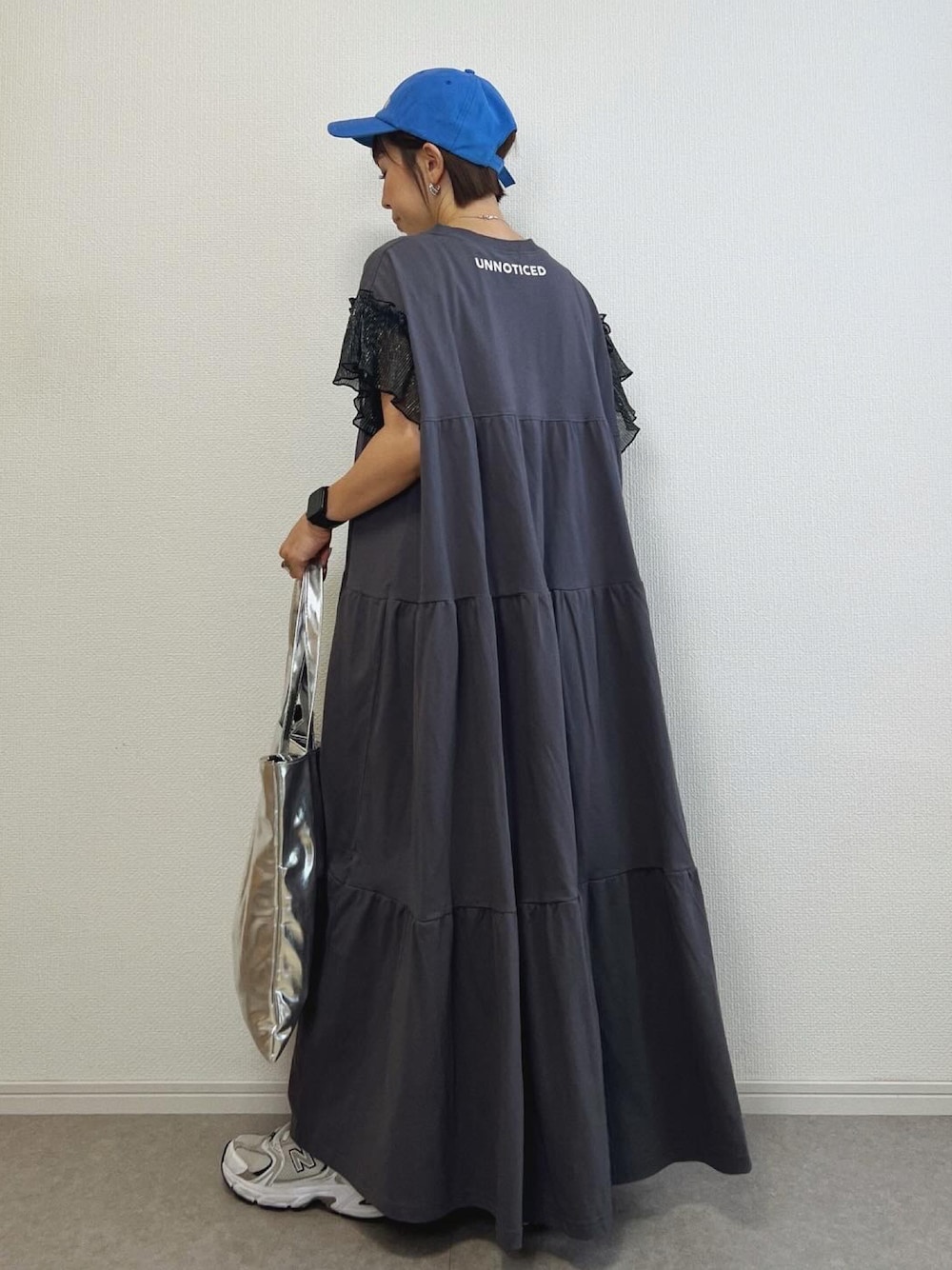 ブラック系のワンピース、シルバー系のトートバッグ、シルバー系のスニーカーを着用したレディースの夏コーディネートの1枚目の写真