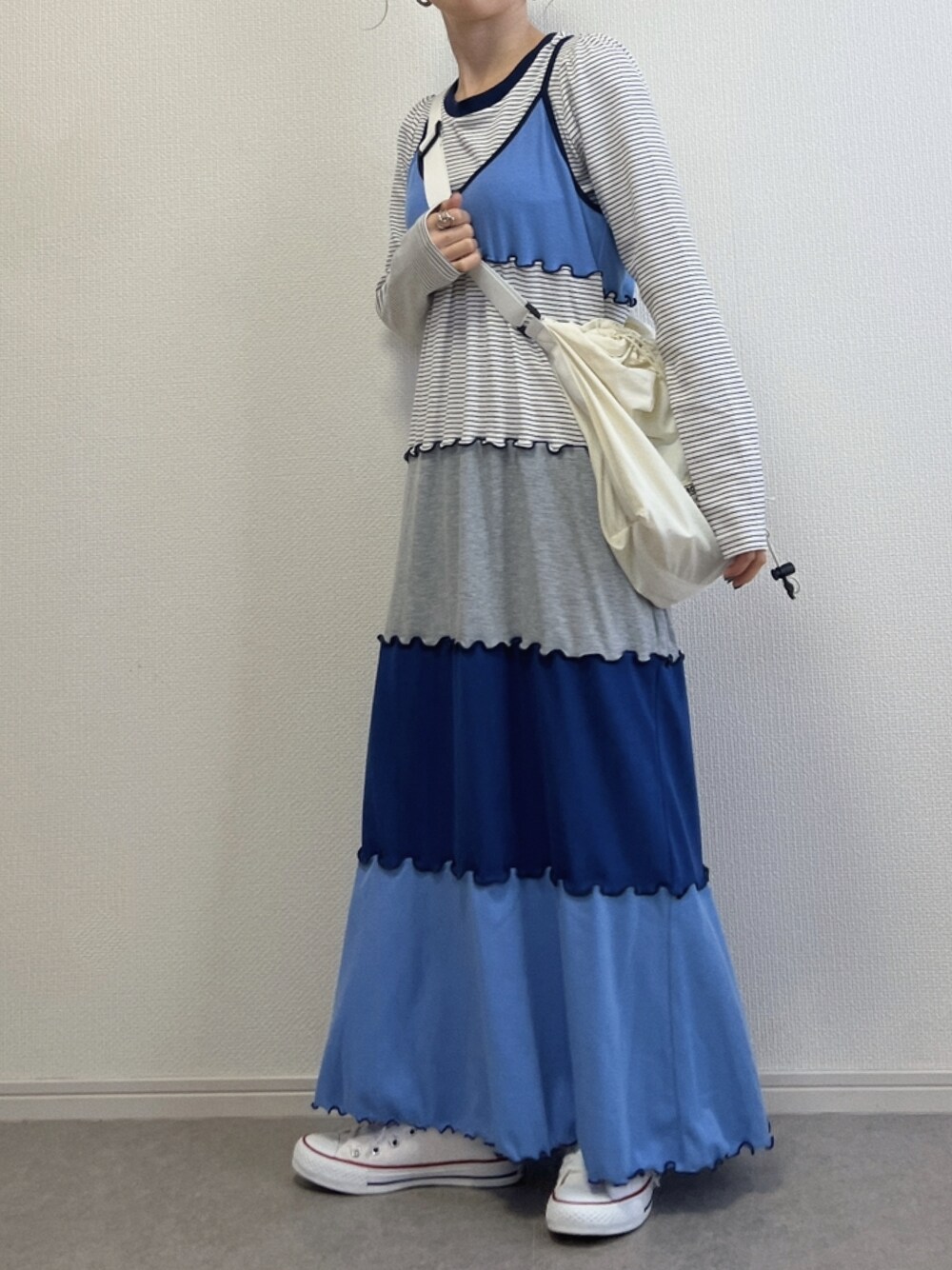 ホワイト系のショルダーバッグ、ホワイト系のスニーカー、ブルー系のワンピースを着用したレディースの春コーディネートの1枚目の写真